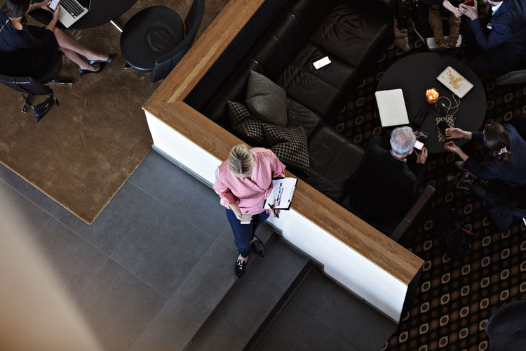 High angle view businesswoman using smart phone while standing on steps by cafeteria