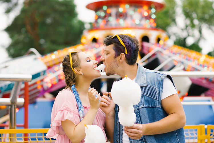 Happy couple in love enjoying each other in an amusement park. a guy and a girl eating cotton candy