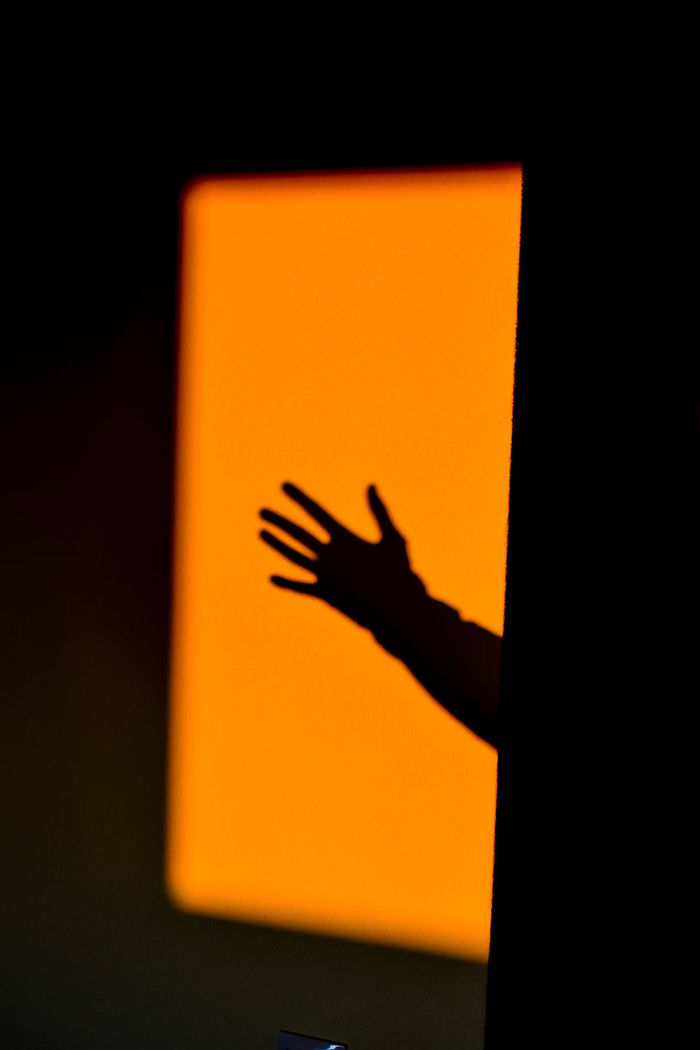 Shadow of person hand on yellow wall