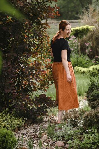 Happy ginger hair woman walking barefoot in the park or garden. freedom and healthy way of life