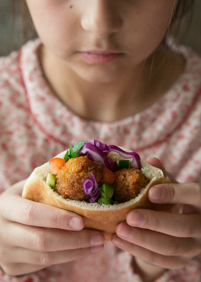 Cropped image of girl eating falafel wrap sandwich