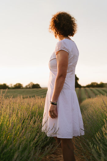 Beautiful woman in a white dress walks in the lavender field.