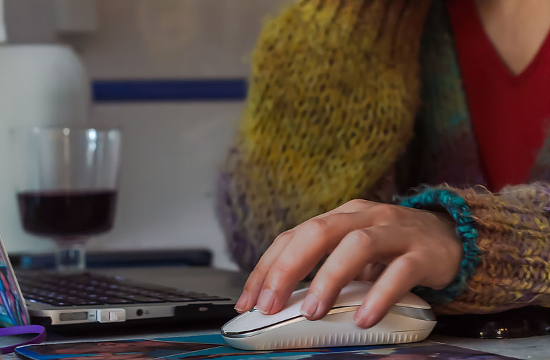 Midsection of woman using computer mouse on table