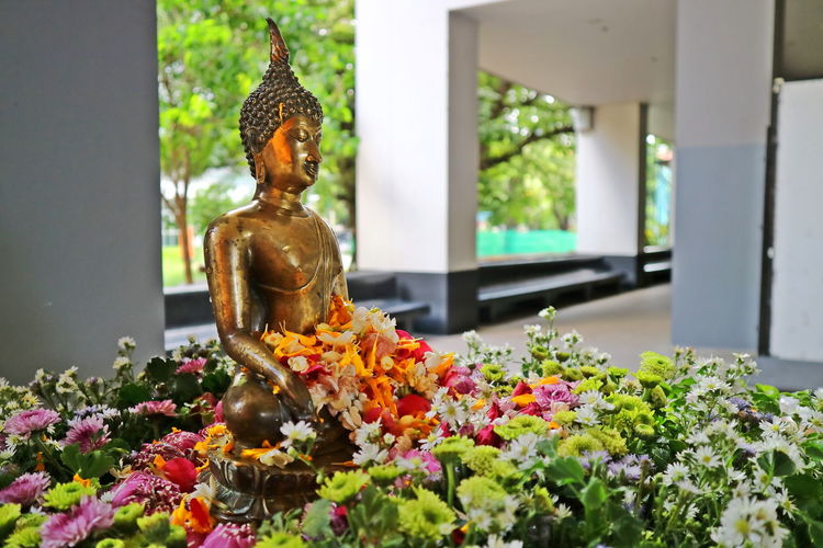 A buddha image with flowers. songkran festival. religion and culture concept.
