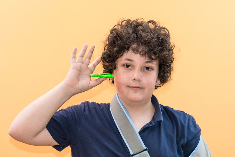 Portrait of boy holding toy against orange background