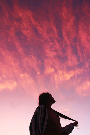 Rear view of silhouette man against orange sky