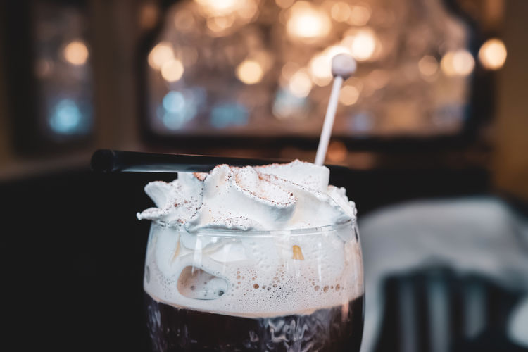 Irish coffee with whipped cream against blurry background