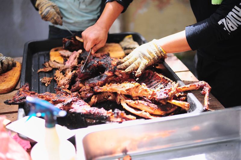 Close-up of hands cutting grilled lamb