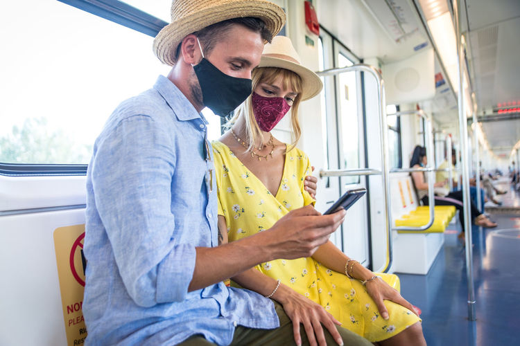 Smiling couple using smart phone sitting in bus