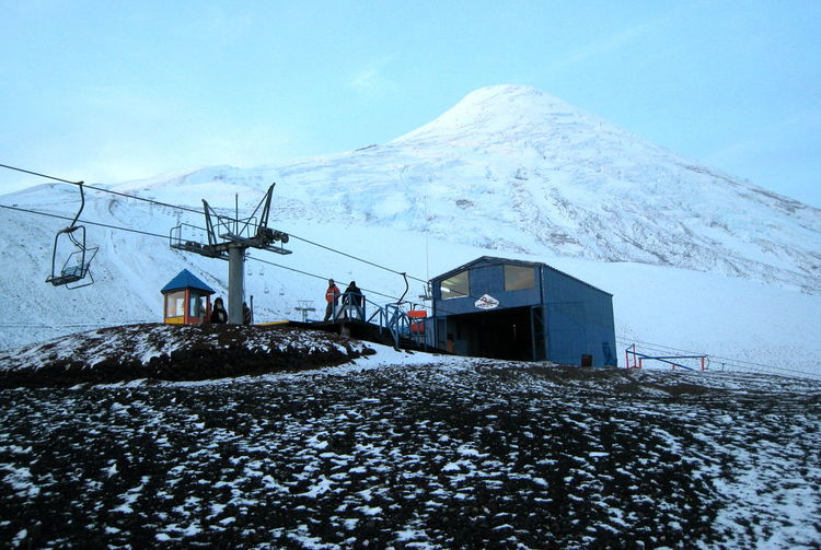 Ski lift station by snowcapped mountain against sky