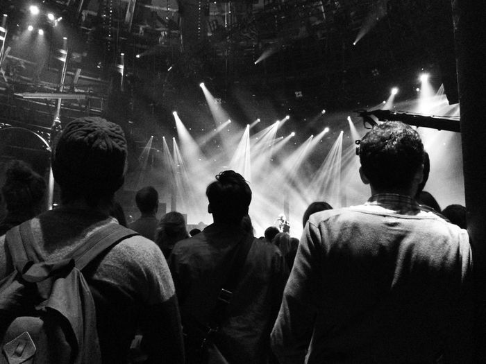 Rear view of people against light beams at music festival