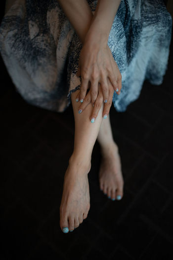 Low section of woman with nail polish on hand and legs