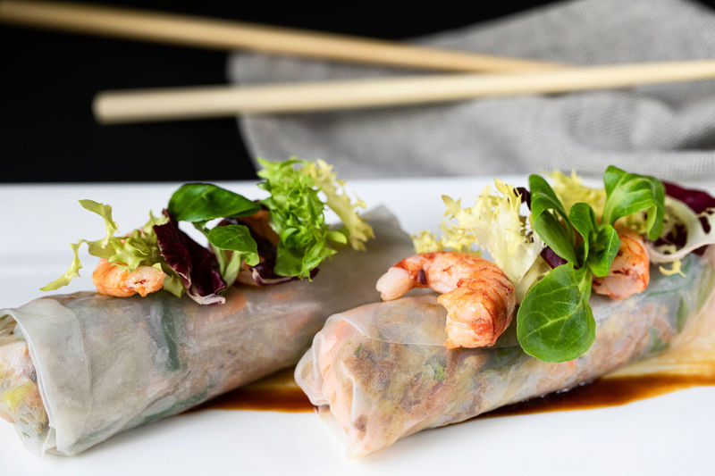 Closeup of delicious duck cannelloni garnished with shrimps and greenery and served on plate in asian restaurant