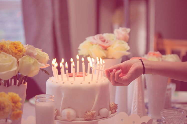 Cropped hand burning birthday candles at home