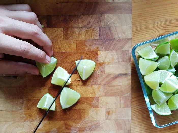 High angle view of person cutting limes on table