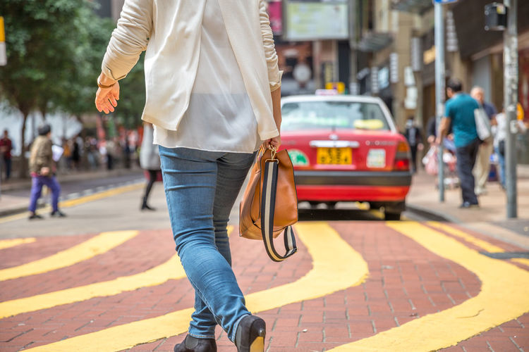 Low section of woman walking on city street