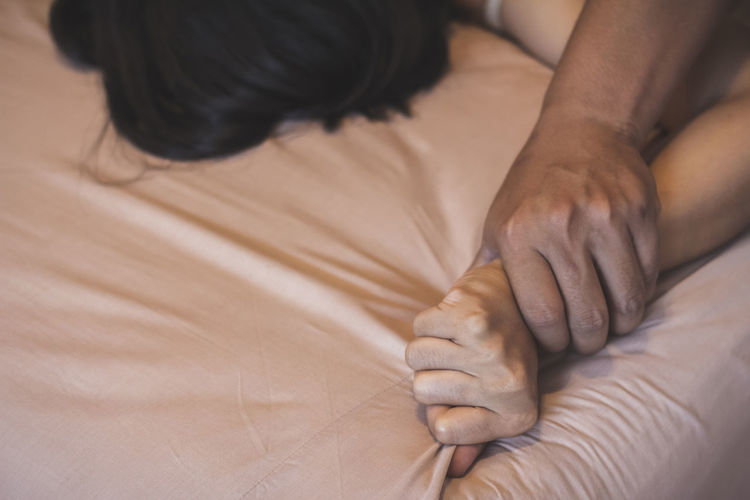 Cropped image of couple doing sex on bed at home