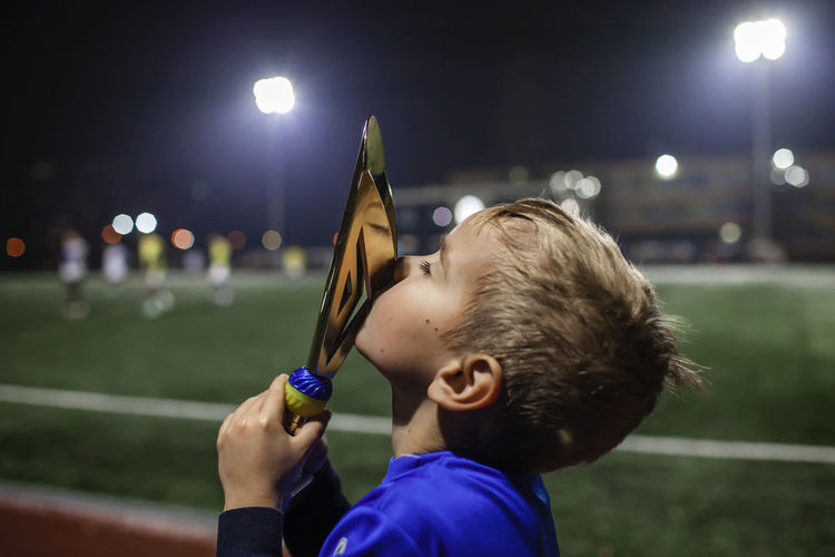 Cute boy kissing trophy