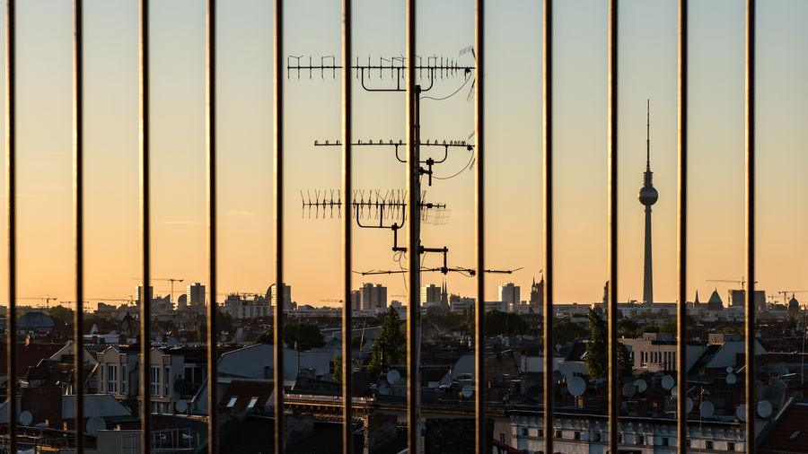 Fernsehturm and cityscape seen through railing during sunset