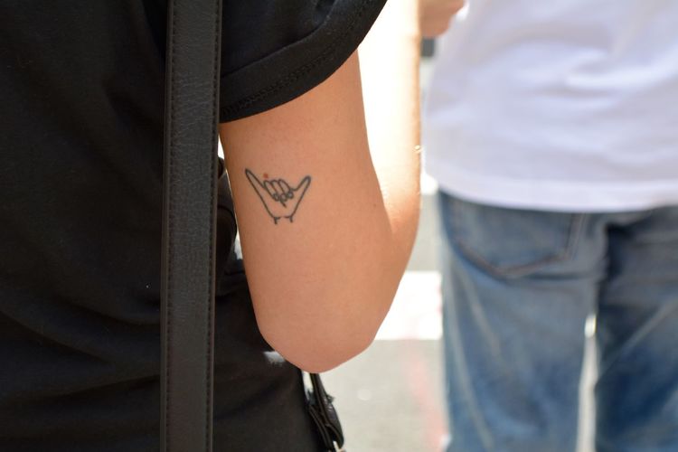 Close-up of shaka sign tattoo on hand