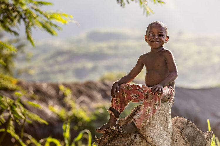 Portrait of smiling boy sitting on rock
