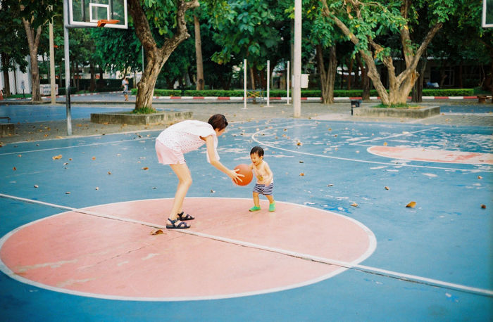 Mother and son playing basketball on court