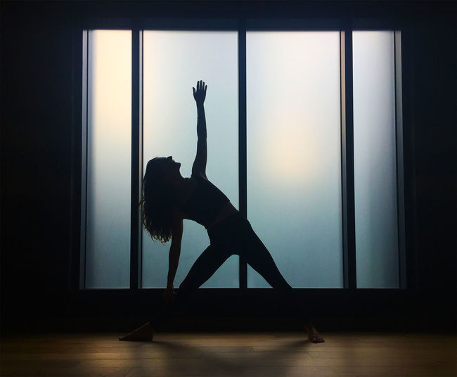 Silhouette of woman stretching indoors