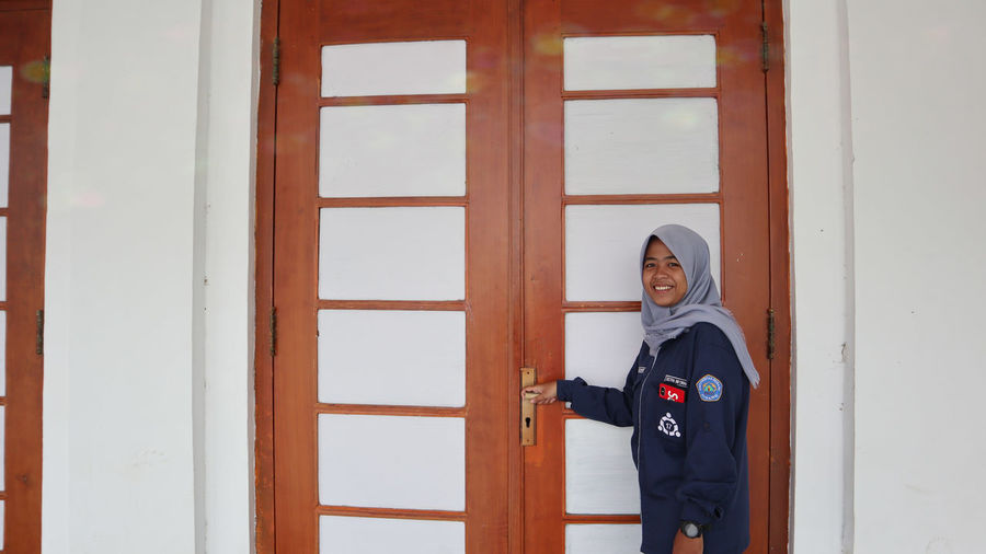 Portrait of smiling woman standing by door