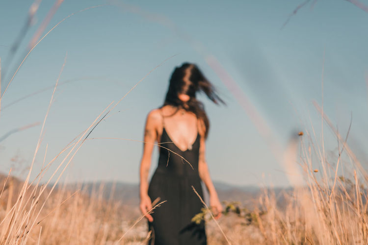 Woman standing on field against sky out of focus.