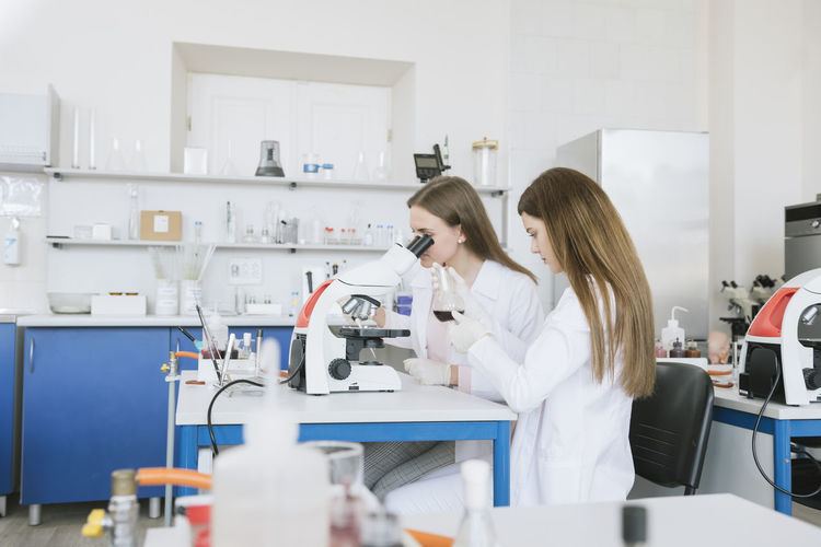 Scientists in white coats doing experiment in lab