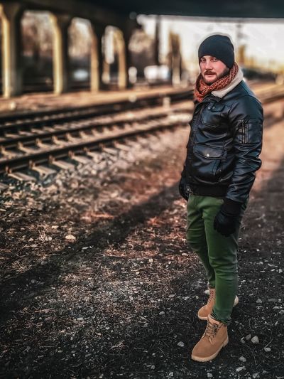 Portrait of man wearing warm clothing while standing at railroad track