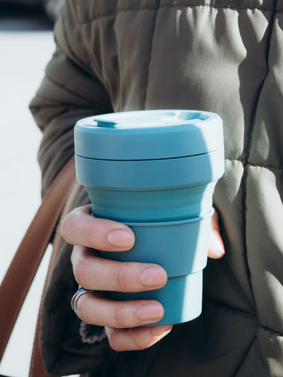 Female hands hold blue reusable coffee mug. sustainable lifestyle. eco friendly concept.