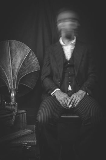 Blurred motion of man sitting on chair by gramophone