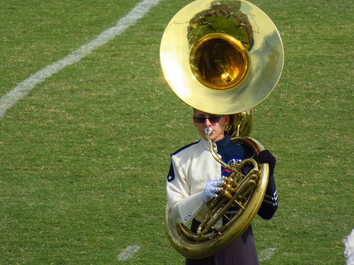 Man playing trumpet while standing on field