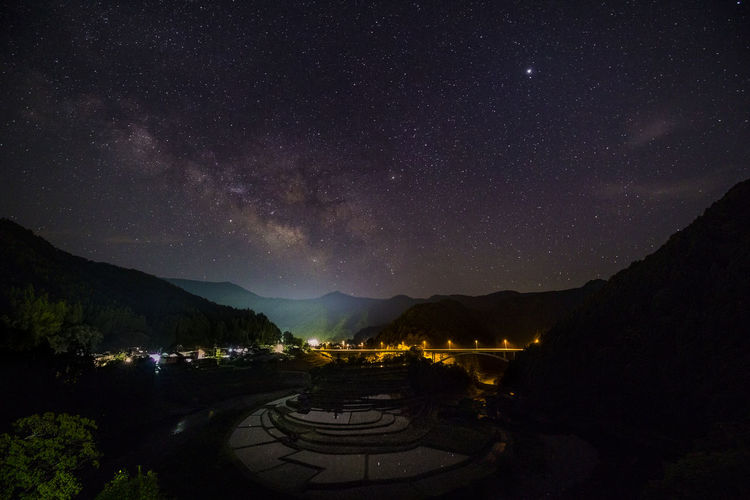 Scenic view of illuminated mountains against sky at night