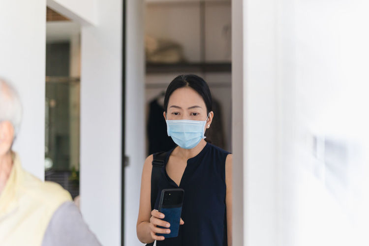 Portrait of woman in medical mask using cell phone