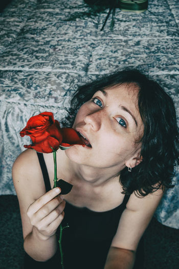 Close-up portrait of woman eating rose flower at home