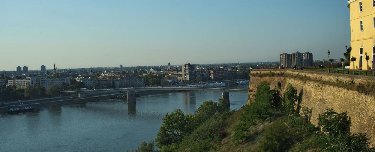 Bridge over river amidst buildings in city against clear sky