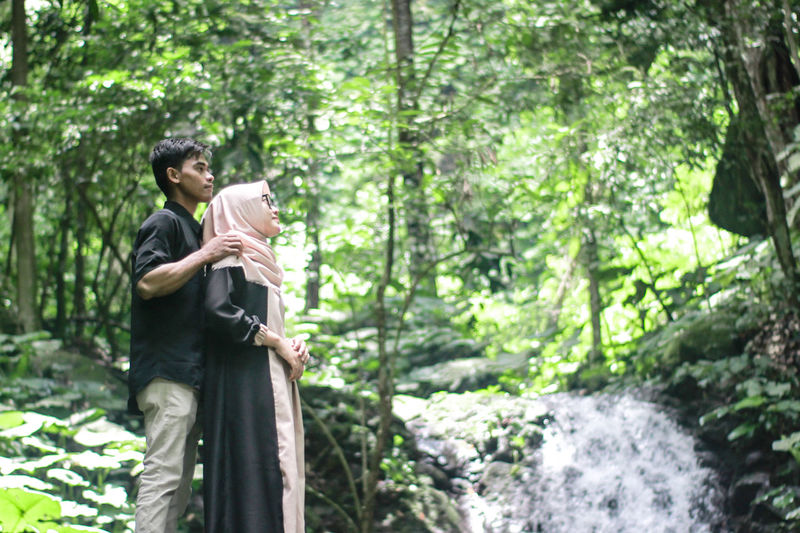Couple standing by waterfall in forest