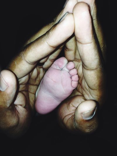 Cropped image of father hands holding baby leg