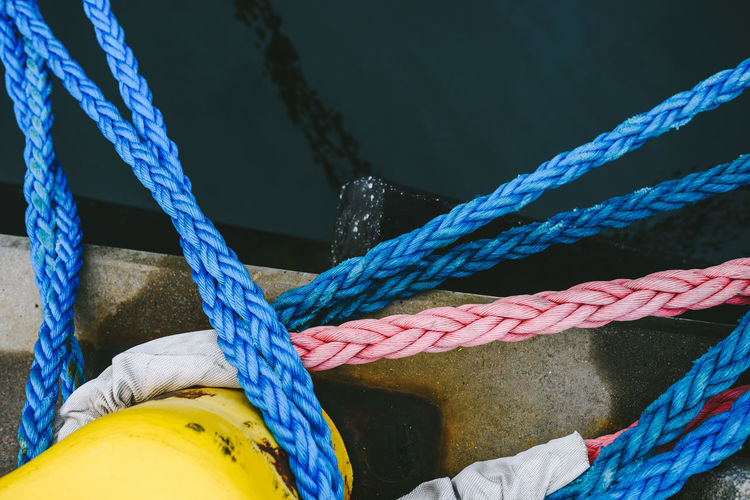 High angle view of ropes tied on bollard at harbor