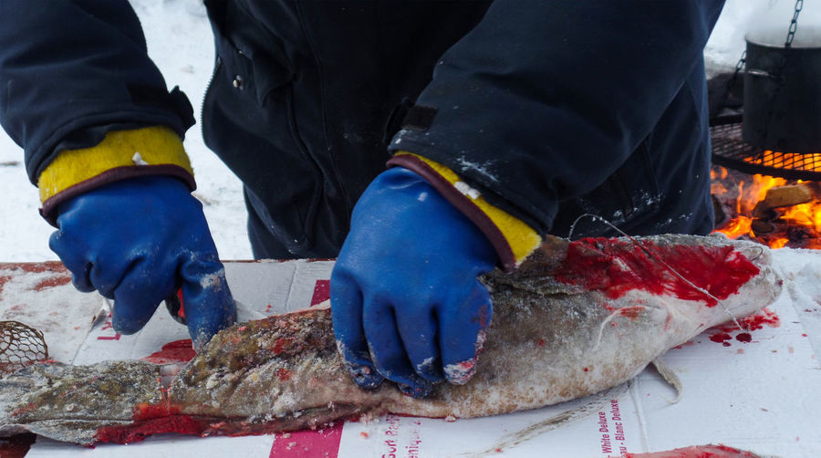 Midsection of person cutting frozen fish on table