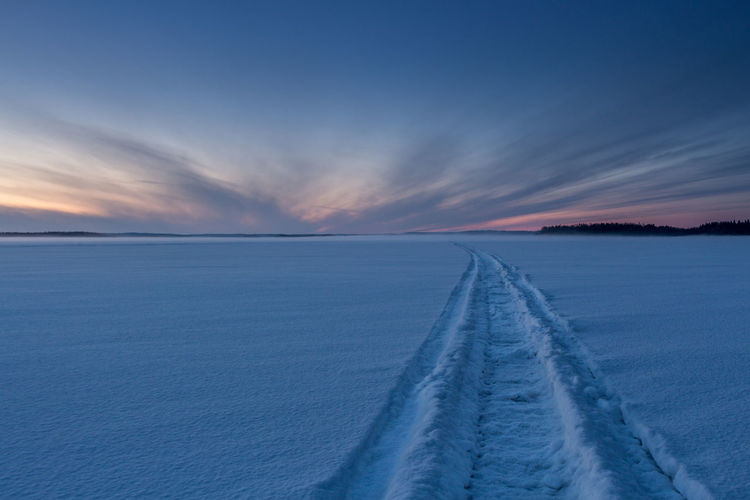 Scenic view of snow covered shore against sky during sunset