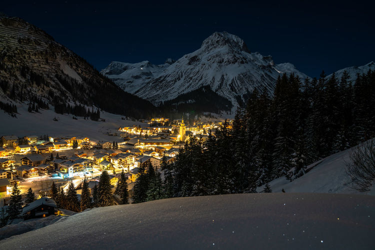 Aerial view of illuminated snow covered mountains against sky at night
