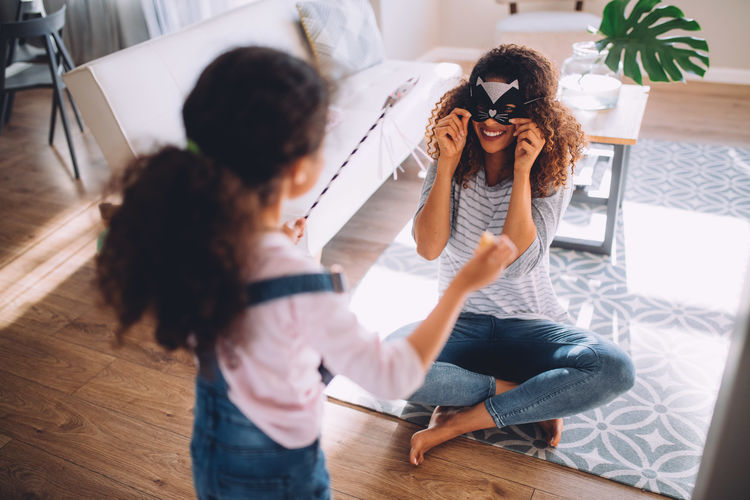 High angle view of mother and daughter playing with props at home