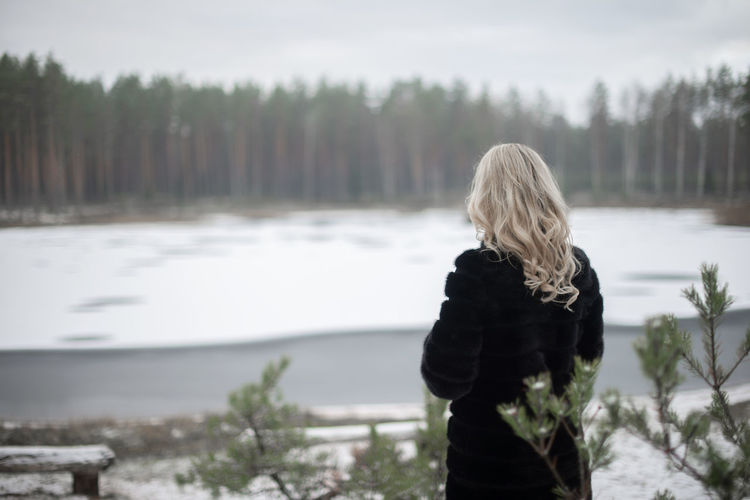 Rear view of woman looking at lake during winter