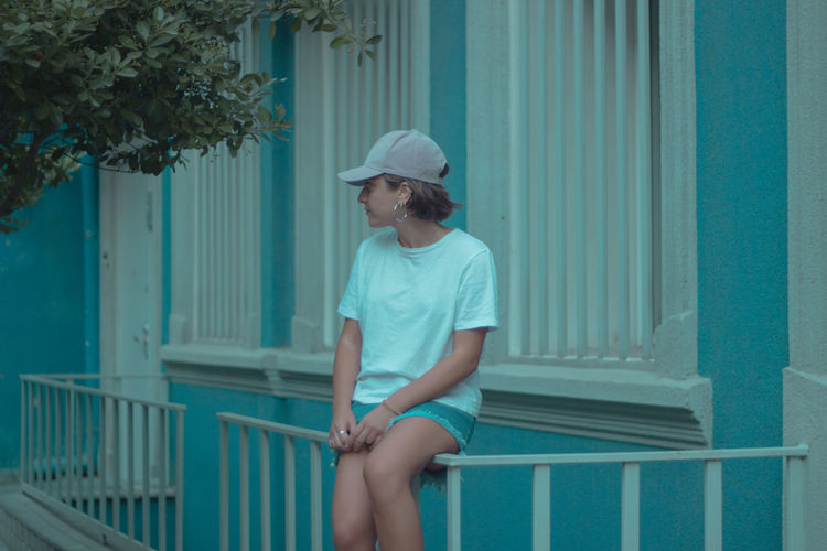 Man looking away while sitting on railing
