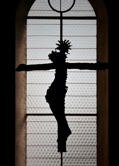 Close-up of silhouette statue against window in church