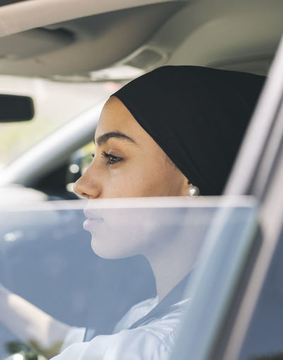 Woman looking through window while sitting in car