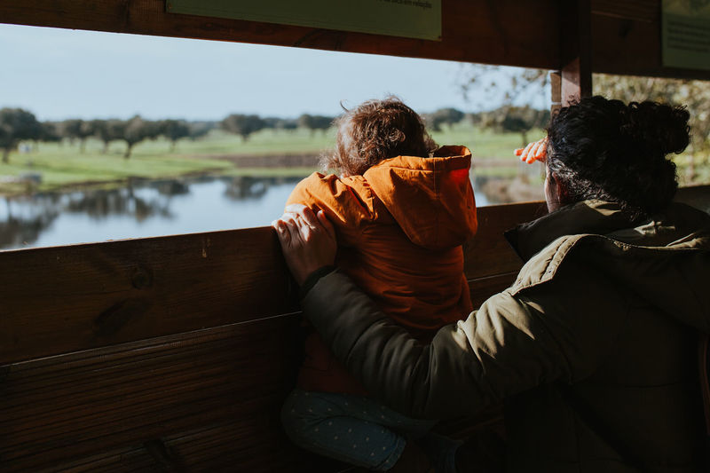 Rear view of couple sitting by lake